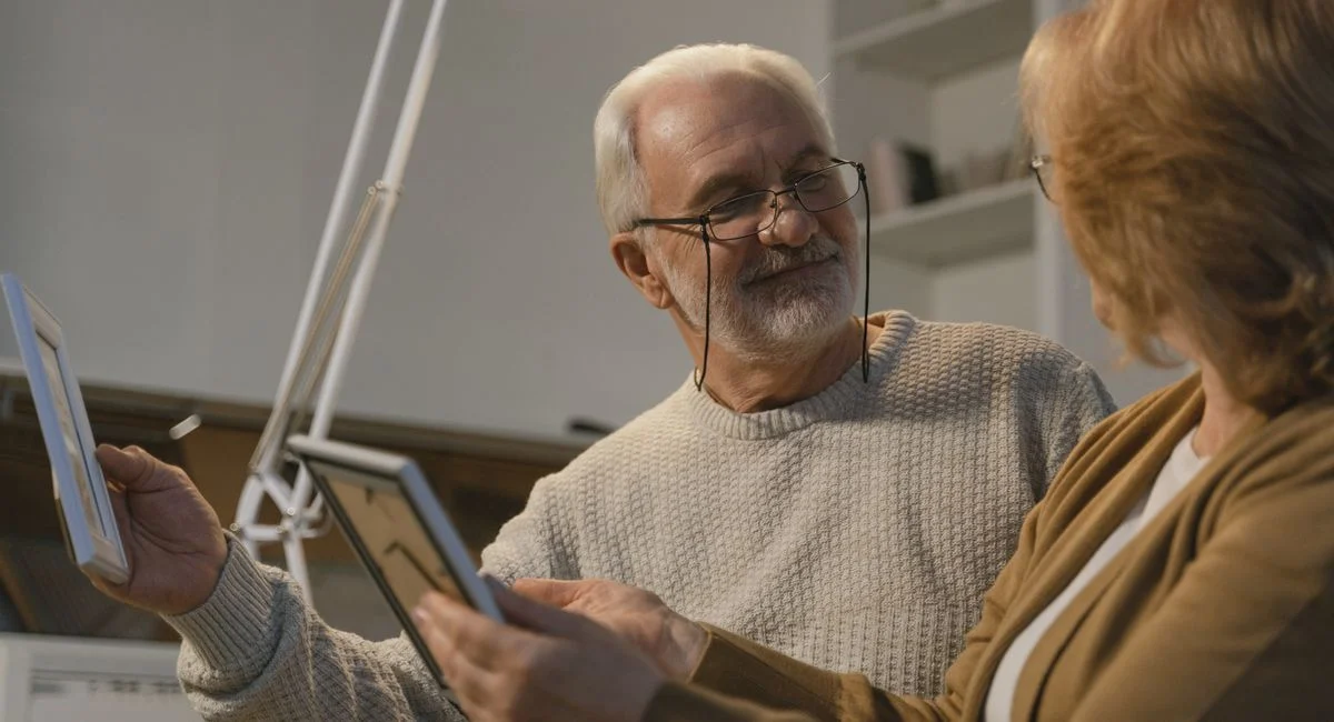Senior couple sharing memories with photo frames in a cozy home setting.