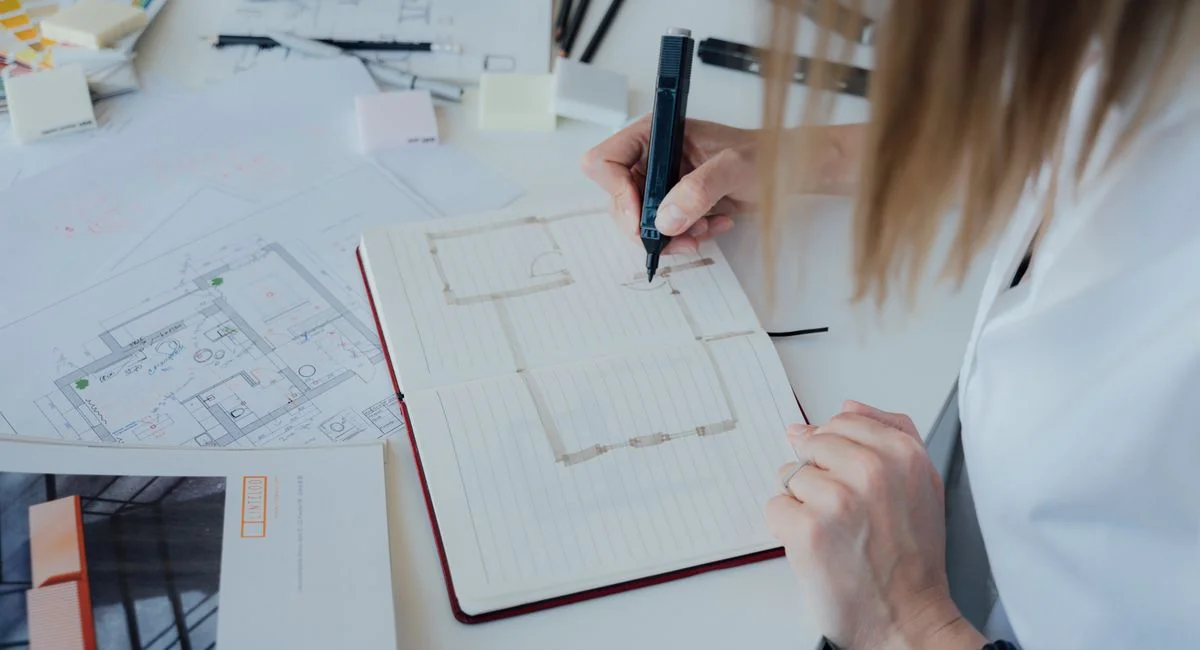An architect sketches floor plans and designs in an organized office environment.