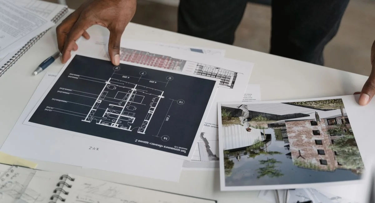 Architect hands reviewing architectural blueprints and design documents in an office setting.