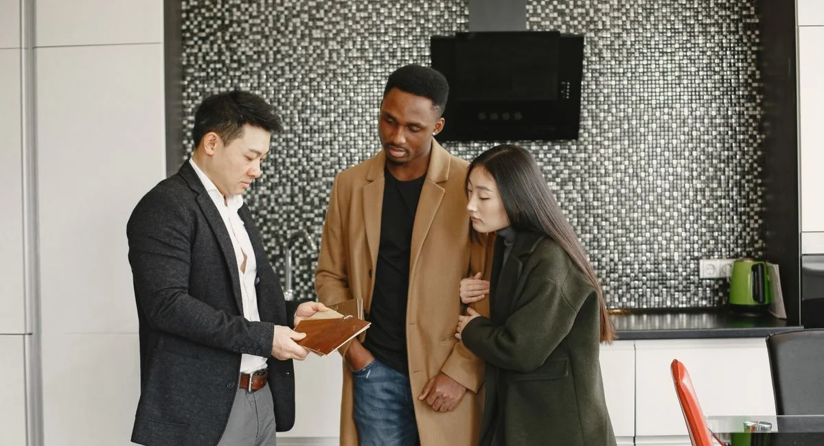 A business meeting in a contemporary kitchen showing diverse professionals discussing strategic options.