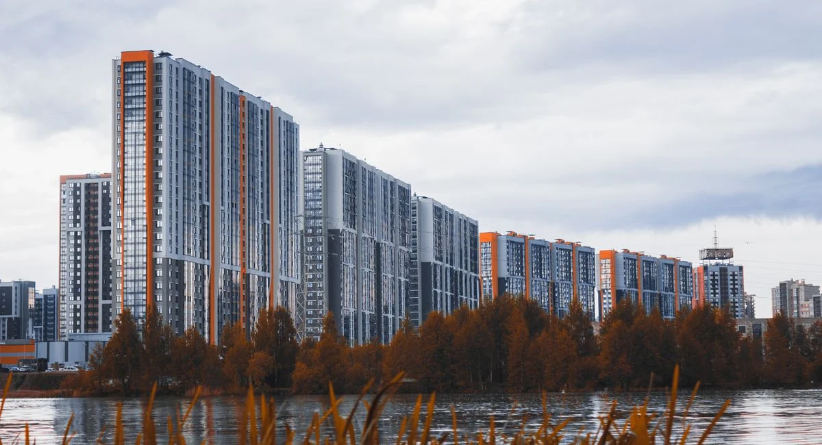 High-rise apartment buildings near a river with autumn foliage.
