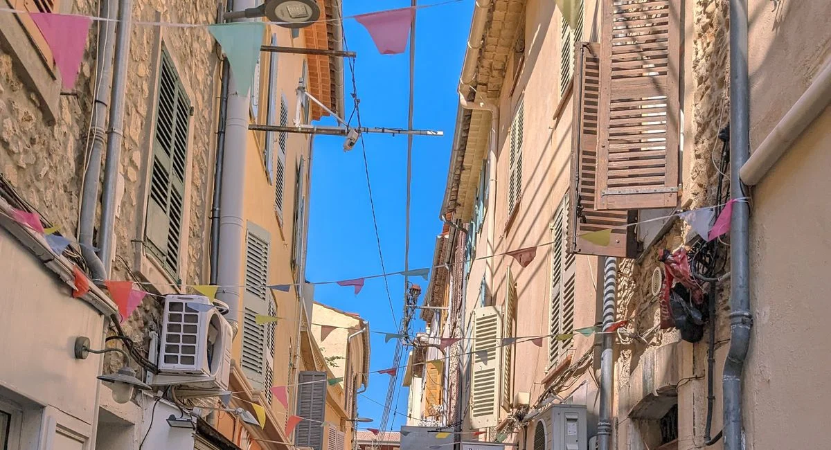 Sunny street in Antibes, France with colorful bunting and quaint architecture. Experience the Mediterranean vibe.