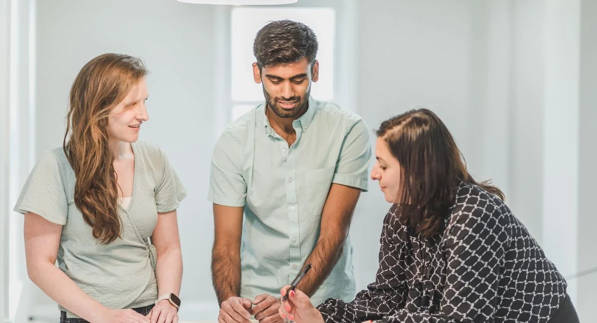 Three professionals engaged in a discussion indoors, possibly real estate related.