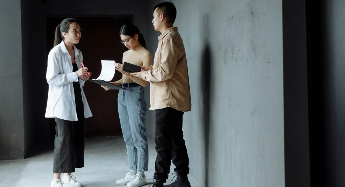 Three colleagues discussing documents in an indoor setting, showcasing teamwork and communication.