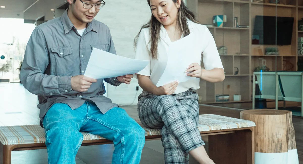 Two colleagues sitting and discussing documents in a contemporary office setting.