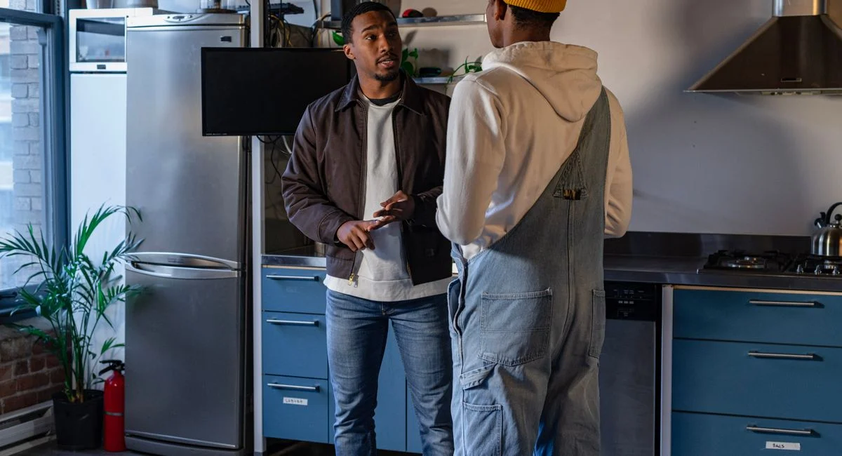 Two friends engaging in a casual conversation in a stylish kitchen.