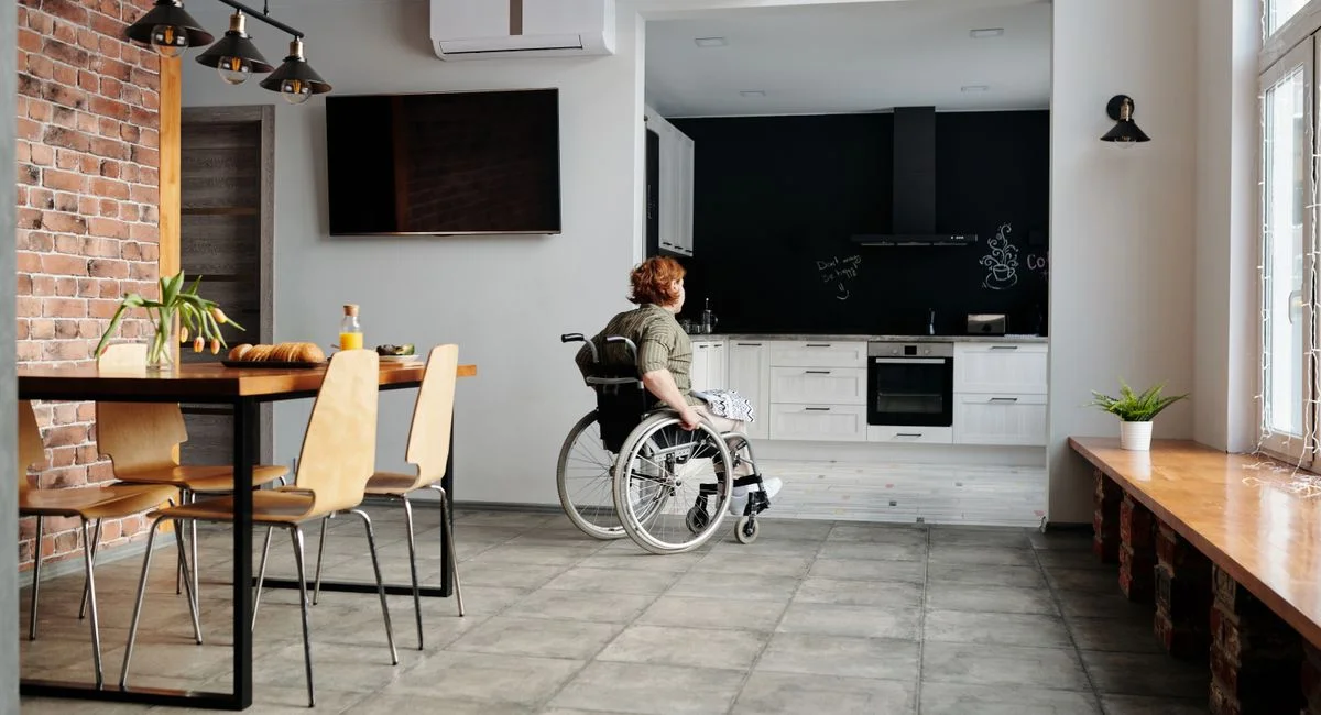 A woman in a wheelchair in a modern kitchen and dining space, highlighting accessibility.