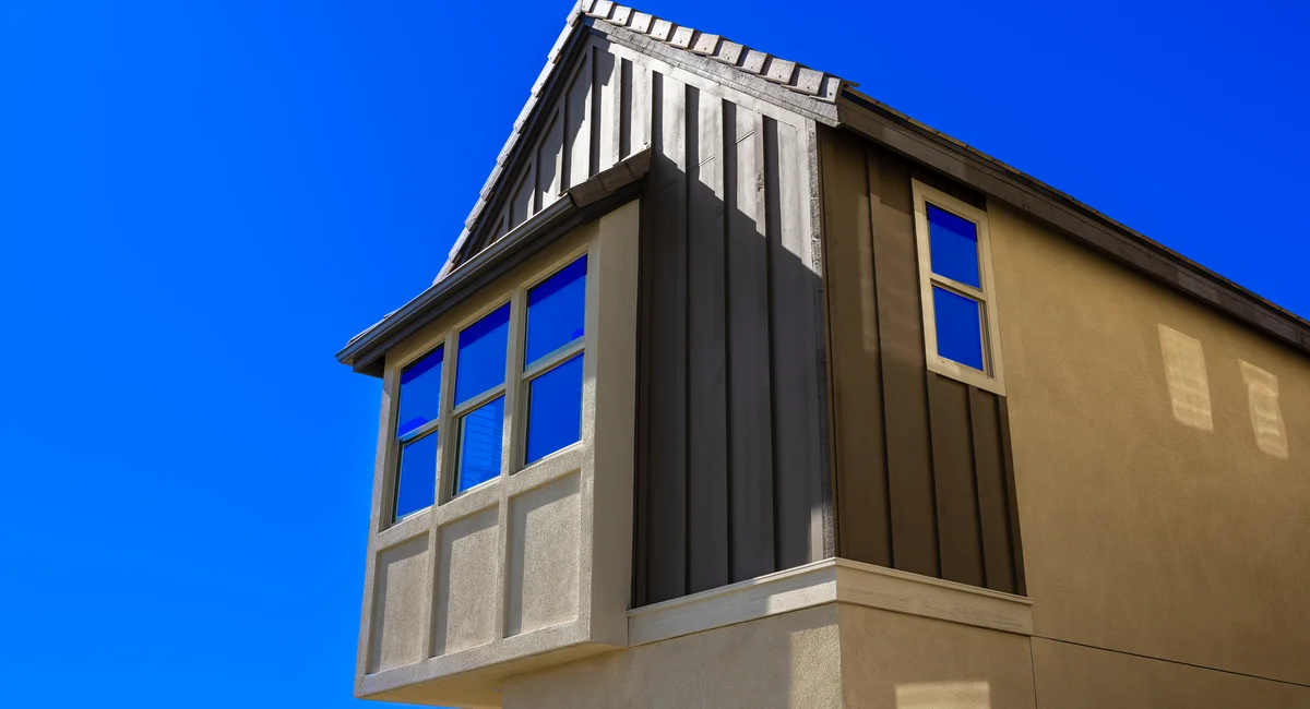Low angle shot of a modern residential building facade against a clear blue sky.
