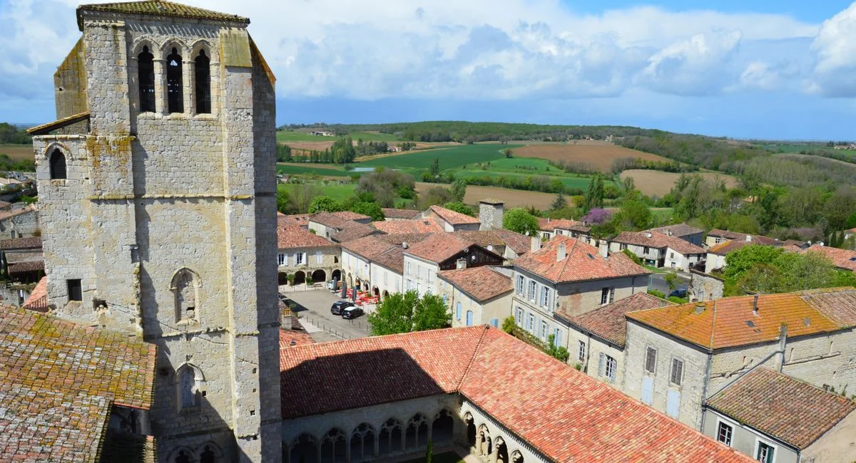 Drone view of La Romieu, France, showcasing historic architecture and countryside.