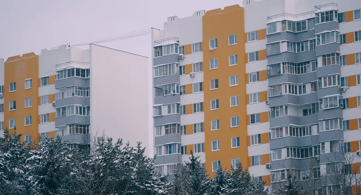 A modern residential apartment building in Moscow, Russia, surrounded by snow-covered trees.