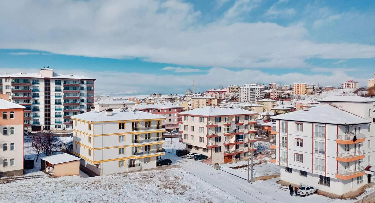 Aerial view of a snow-covered cityscape showcasing residential buildings under a blue sky.