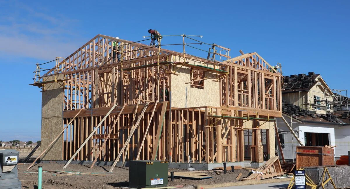 Wood framing of a new house being constructed under a clear blue sky in Sacramento, California.