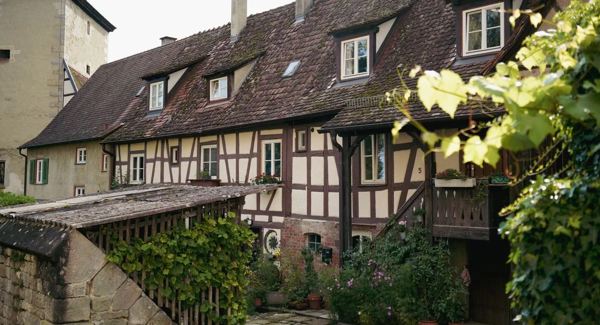Traditional half-timbered house in a picturesque European village with lush greenery.