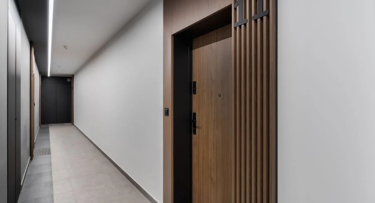 Sleek and modern apartment corridor featuring a wooden door with room number 11 in a minimalist design.