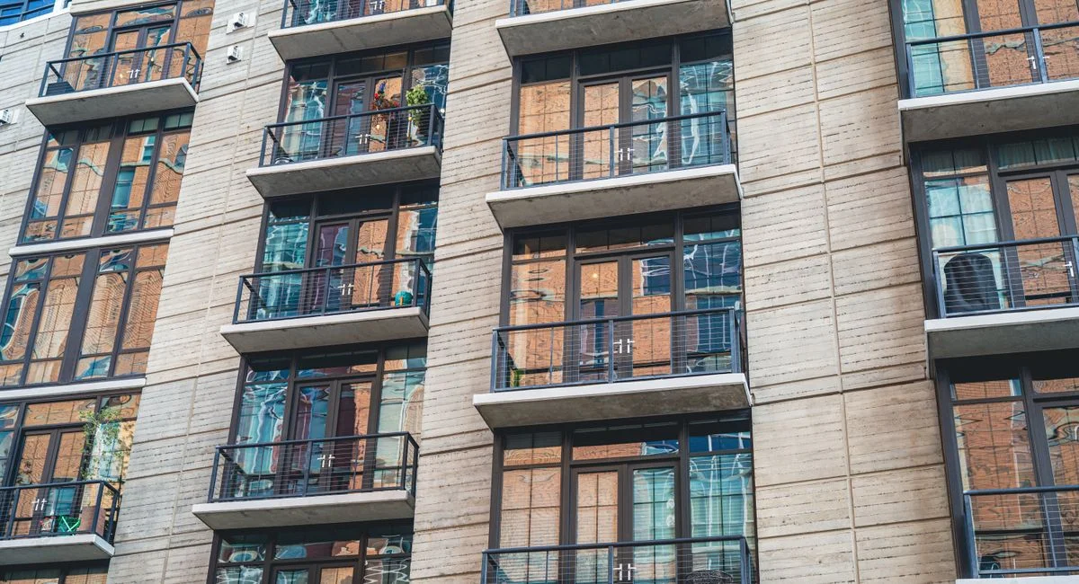 Contemporary apartment building exterior with concrete facade and glass balconies.