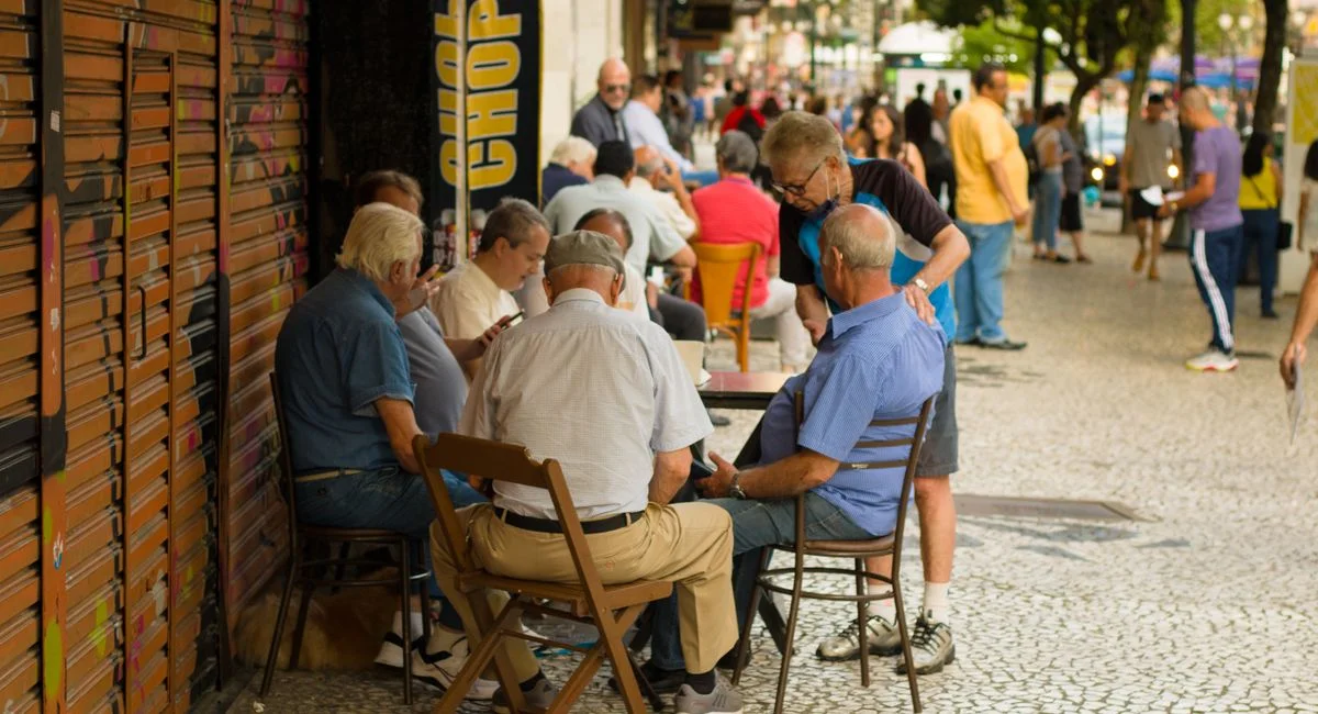 Elderly men enjoy leisure time sitting together outdoors in an urban setting, promoting social connections.
