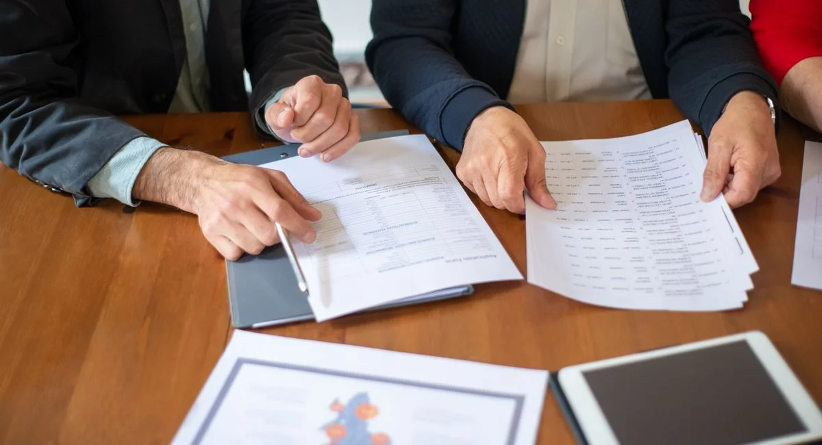 Two business professionals discussing and reviewing documents during a meeting.