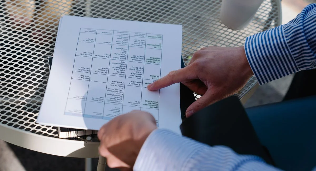 Professional reviewing a document outdoors at a table during a business meeting.