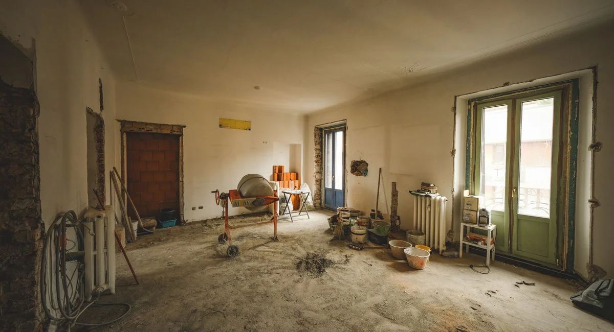 Wide view of a sunny room under renovation with construction materials and tools present, ideal for home improvement concepts
