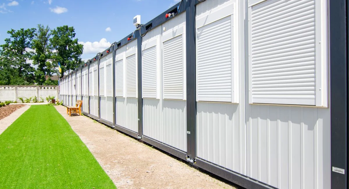 Exterior view of modern container homes with metal siding and adjacent landscaped yard.