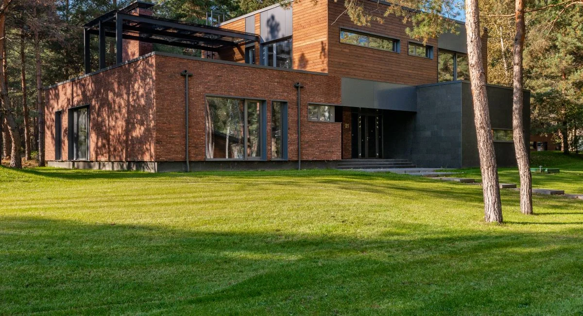 Contemporary house with large windows surrounded by lush greenery and trees.