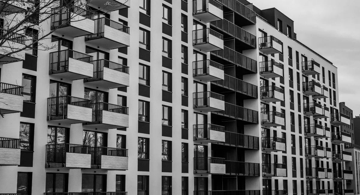 Black and white photo of a contemporary apartment building with multiple balconies.