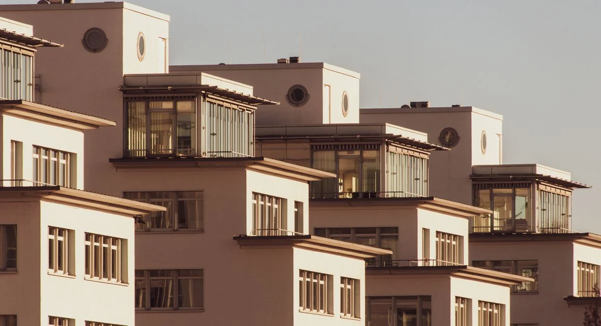 Explore modern white apartment blocks with stylish glass features, bathed in soft daylight.