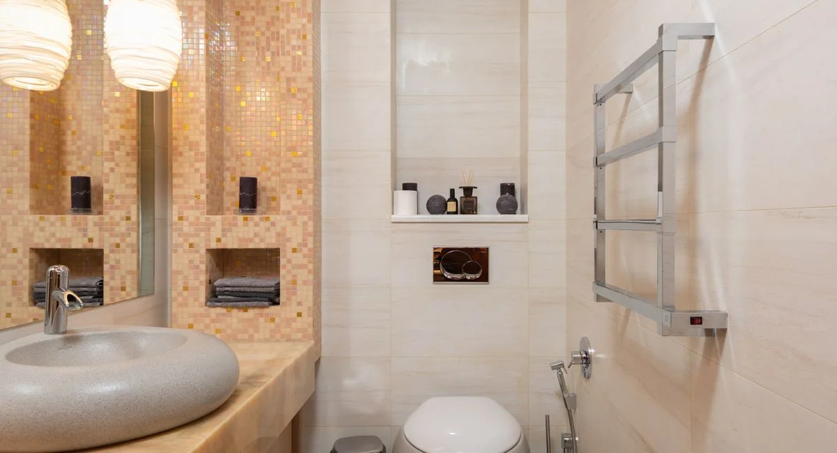 Interior of small light bathroom with ceramic sink and wall mounted toilet in modern apartment