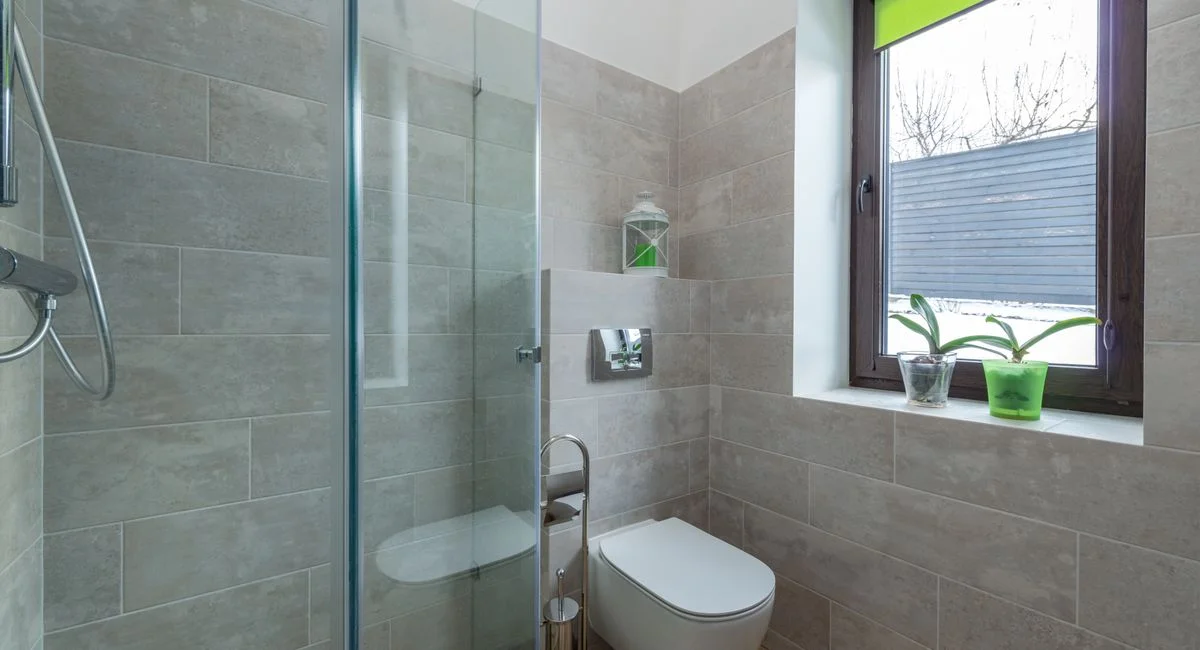 Contemporary bathroom featuring a glass shower, window, and minimalist design elements.