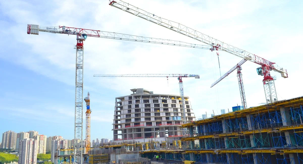 Urban construction site featuring multiple tower cranes against a city skyline.