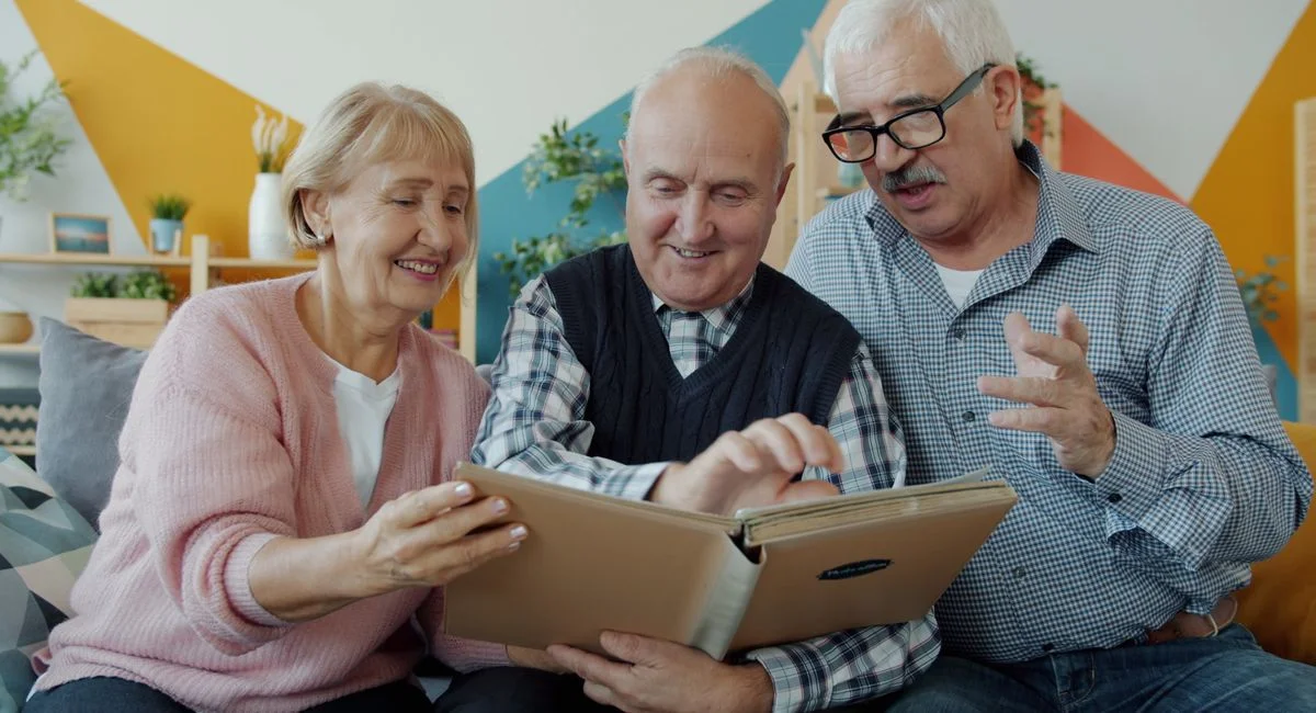 Elderly friends enjoying memories together through a photo album.